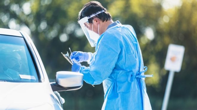 doctor collects COVID-19 tests from drive through testing sites