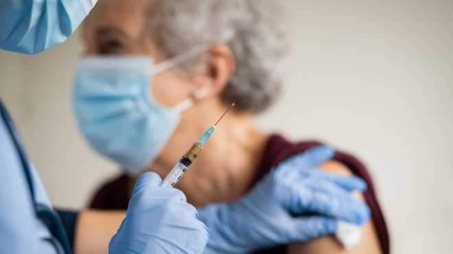 Older woman gets fourth shot of COVID-19 vaccine
