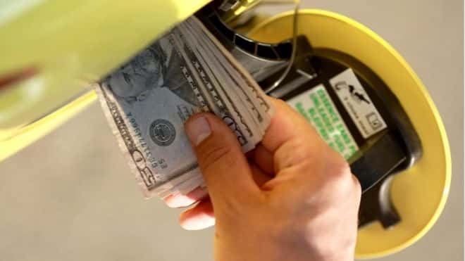 Money going into gas tank of yellow car to show how gas prices are rising.