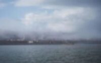 Low clouds over water beneath an overcast sky